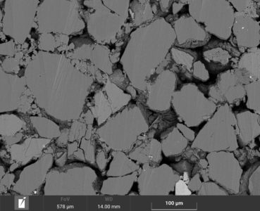 Scanning electron microscopy image of a reservoir rock (sandstone). The pores within the rock are filled with oil. The shape and size of pores controls the storage capacity and producibility of oil.